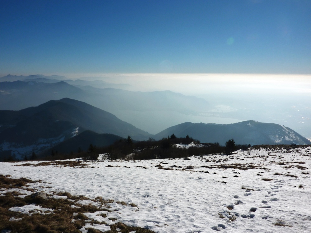 Il lago e le torbiere sfumano nel controluce dalla cima del Bronzone