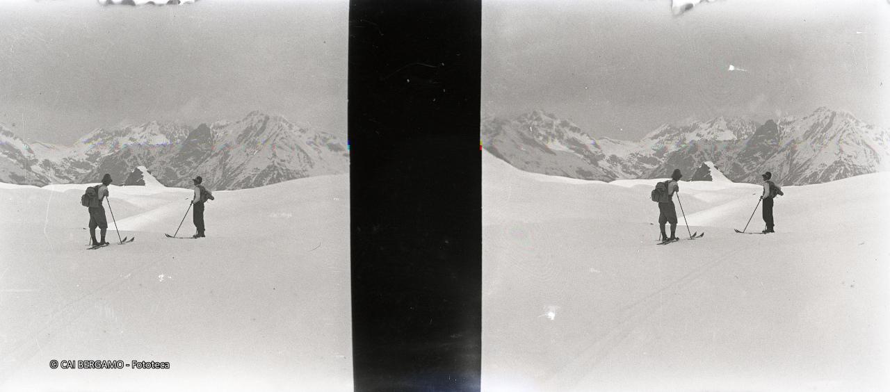 Scialpinisti su pianoro con vista su cime circostanti