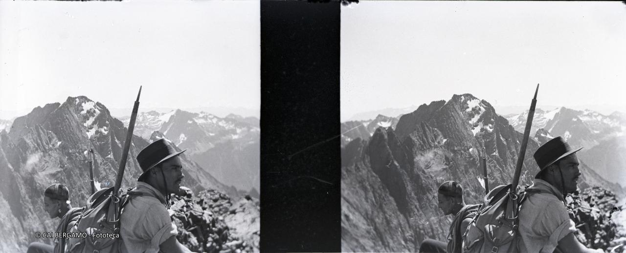 Bel primo piano sul Redorta  con zaino in spalla e piccozza e vista sul Dente di Coca e Pizzo di Coca