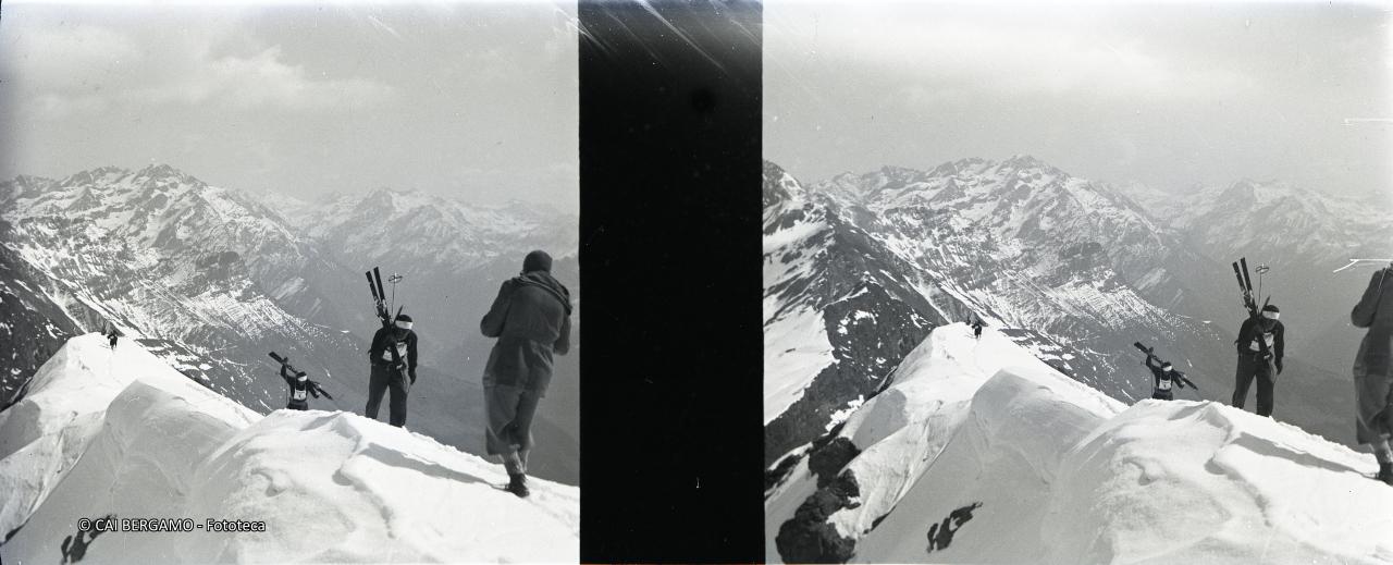 Concorrenti con gli sci a spalla verso il Madonnino e sullo sfondo la Valbondione