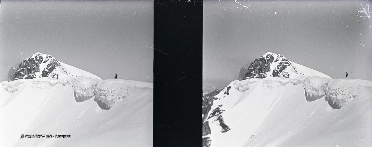 Sciatore sul crinale innevato e ghiacciato con la Punta Rocca sullo sfondo