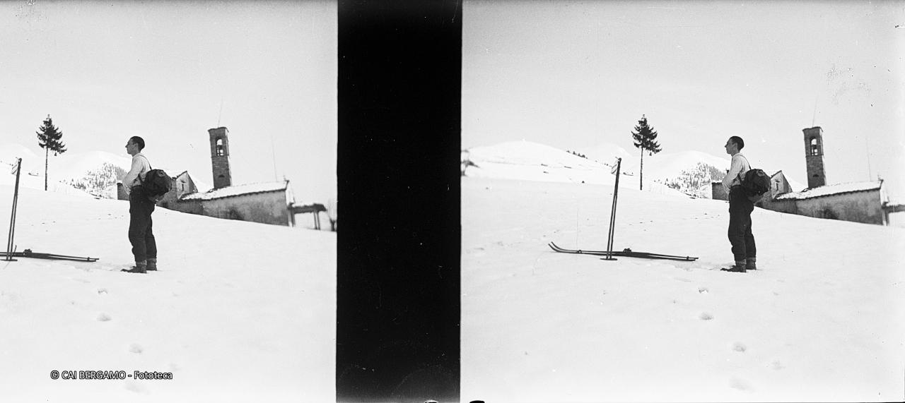 Sciatore con sci a riposo  e chiesetta di S.Antonio al monte Alino