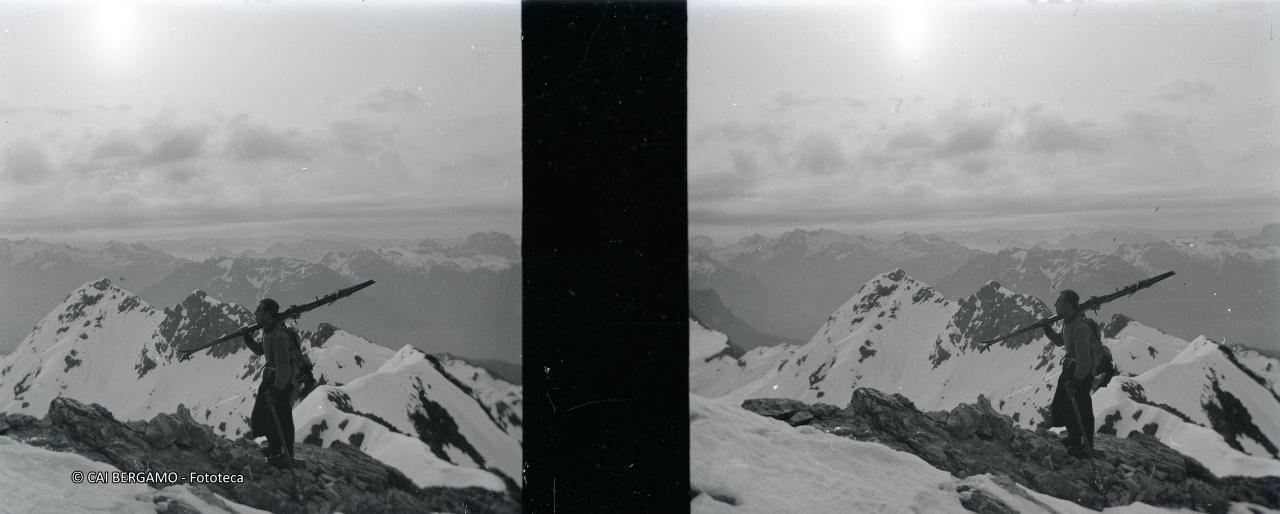 Scialpinista su terreno roccioso con sci a spalla