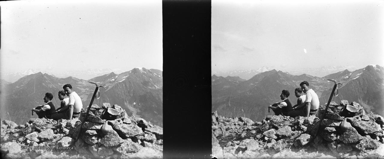 Vista panoramica in vetta al Pizzo del Becco con alpinisti e piccozza in primo piano