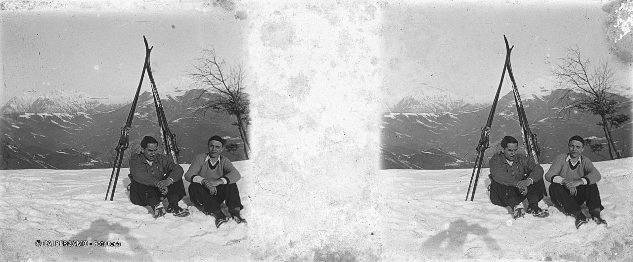 Sciatori seduti nella neve con sci alle spalle