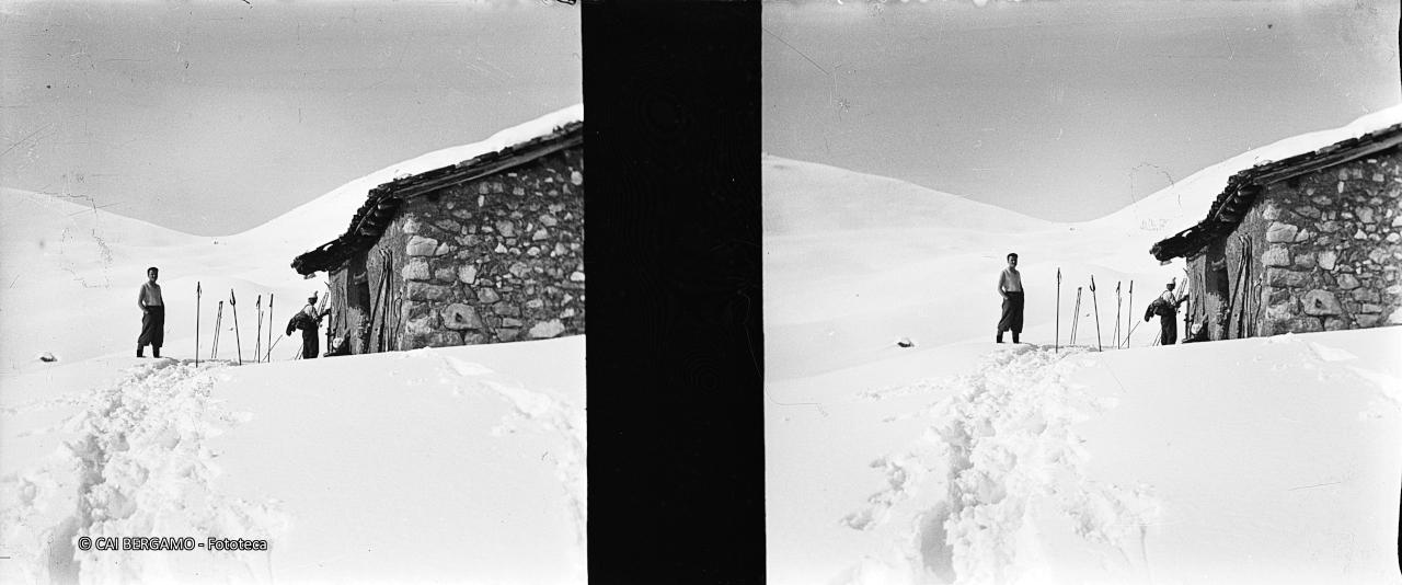 Skiatori tra bastoncini e ski davanti al  vecchio bivacco Mistri