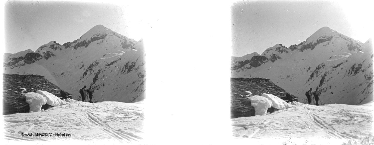 Skiatori a lato di malga e sullo sfondo monte Cavallo