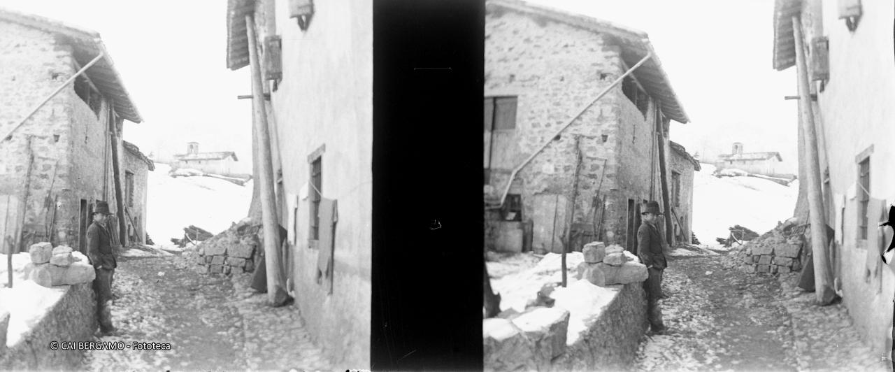 Scorcio tra case, con ragazzo e chiesetta poco sopra tra la neve