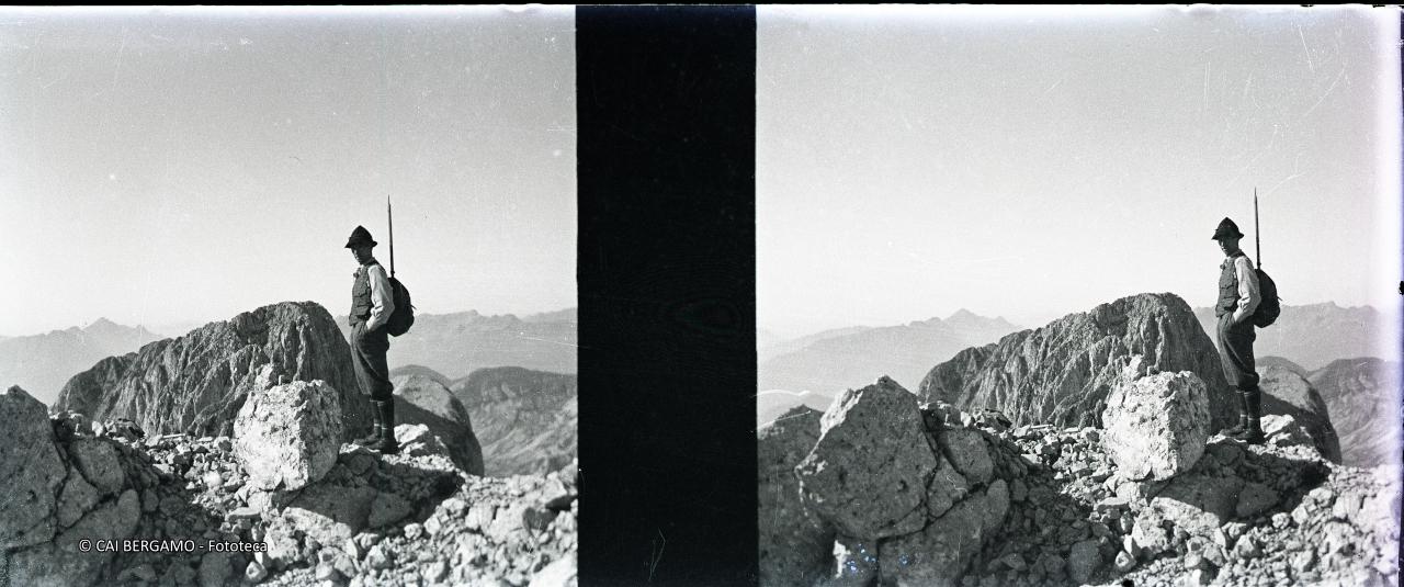 Foto ricordo in vetta con mani in tasca e piccozza nello zaino