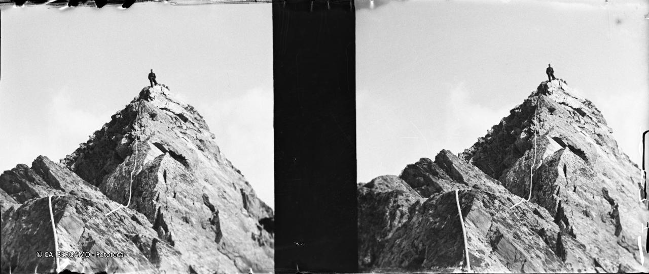 Alpinista in vetta e corda lungo la cresta