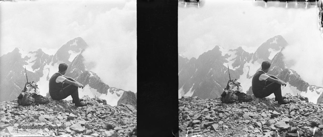 Seduto con sguardo sul Pizzo del Diavolo,  con zaino, scarponi e piccozza alle spalle