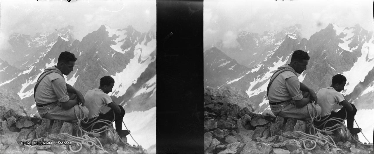 Due alpinisti Seduti con corda al loro fianco e bocchetta di Podavit con pendici del Diavolo di Tenda