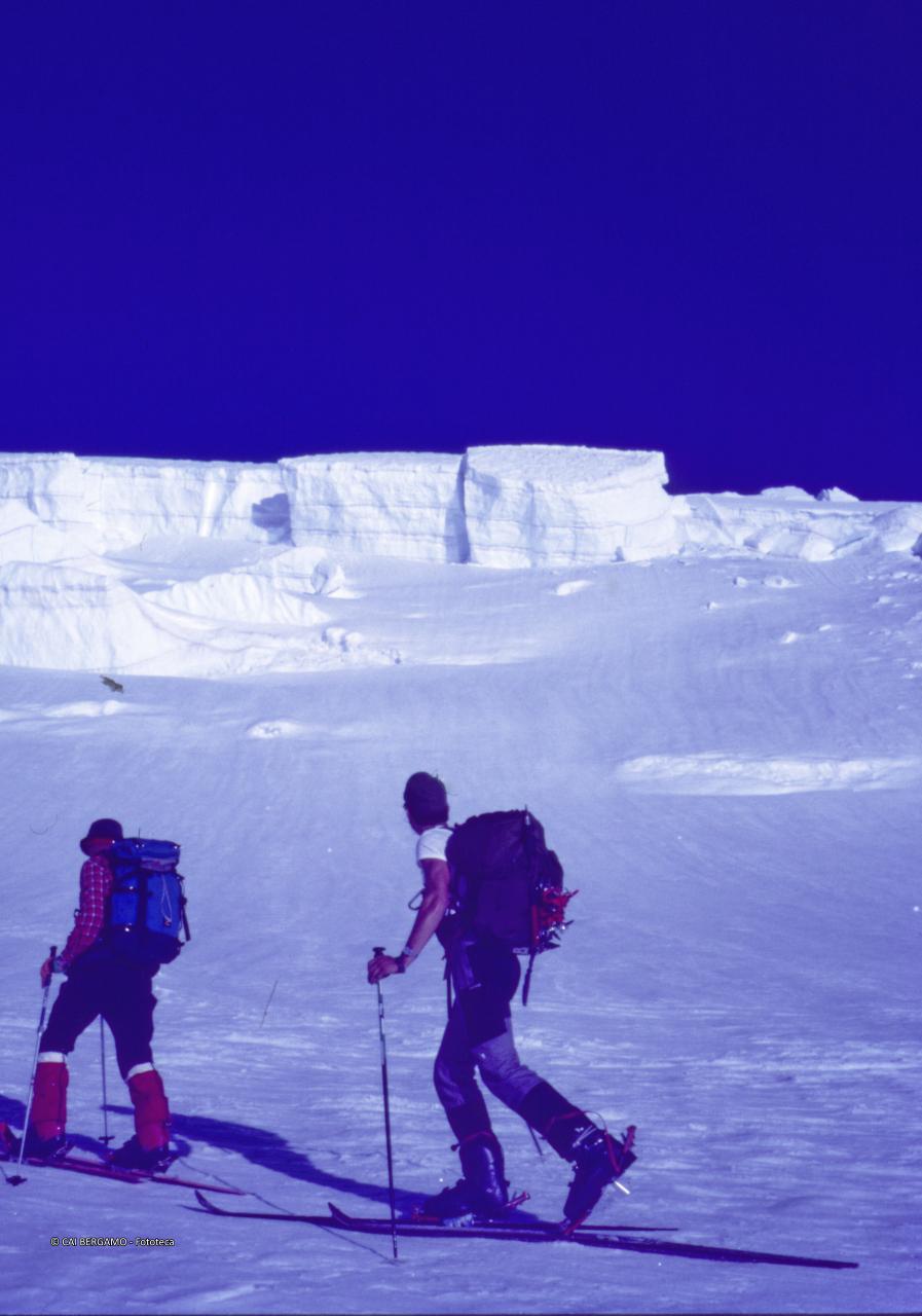 Scialpinista con sguardo verso alti cumuli di neve
