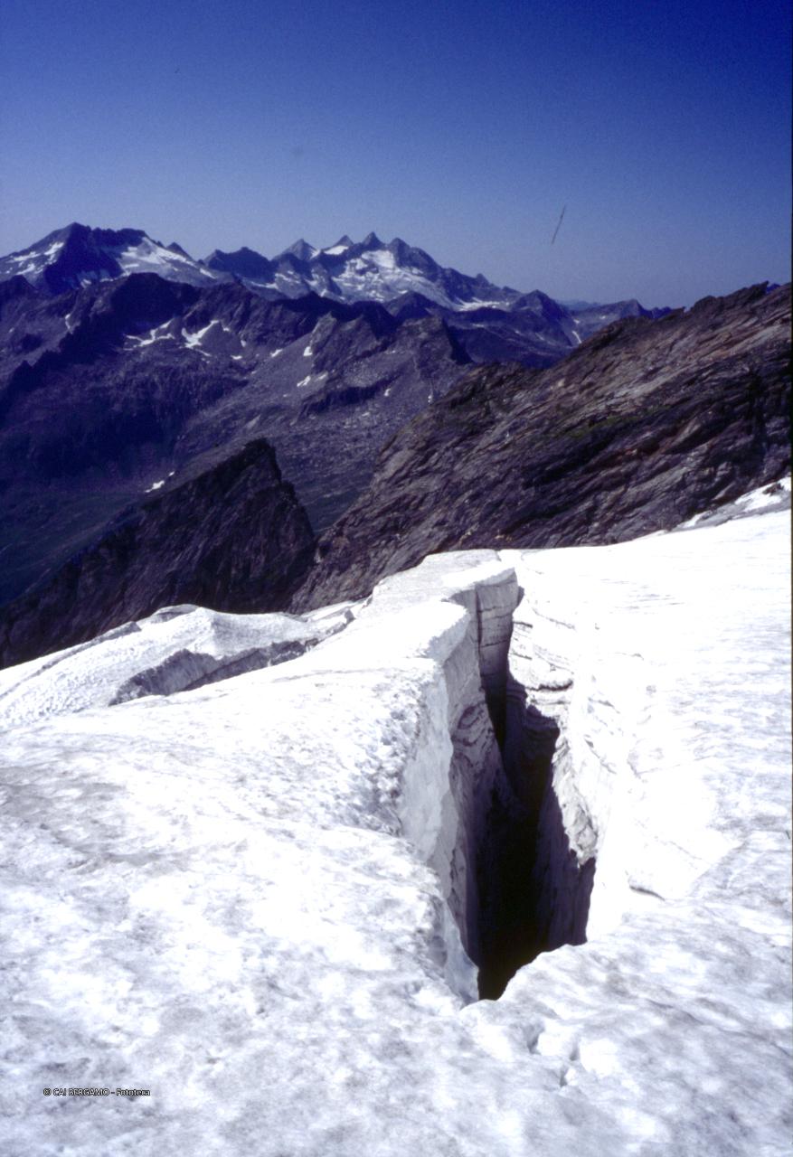 Profondo crepaccio in primo piano con gruppo del Gran Paradiso sullo sfondo