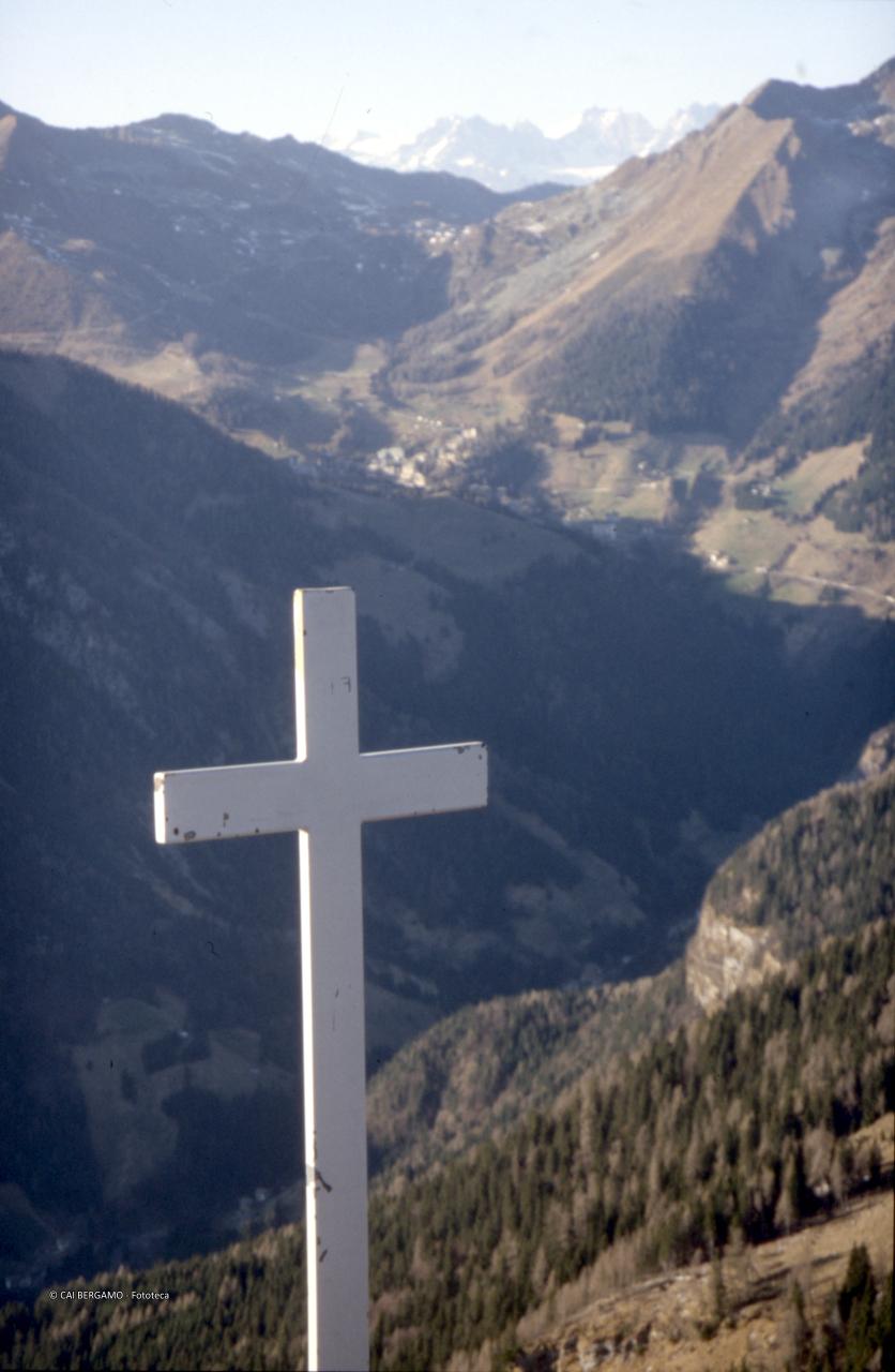 Croce sul Pizzo Badile con vista su Carona